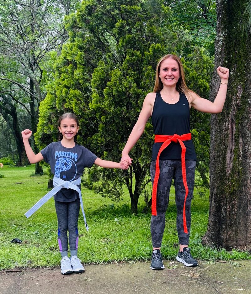 La Dra. Ligia Arechavala con su hija en un parque, las dos con cinta de karate